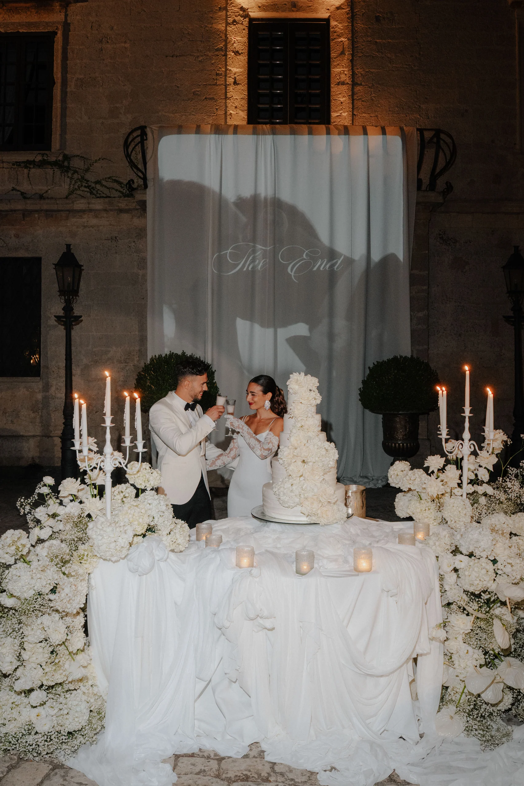Salvatore and Giulia toasting beside their wedding cake at Castello Monaci